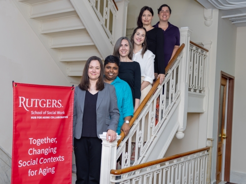 Staged photo of six people on stairs with organizational banner