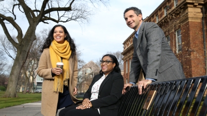 Three adults outside on campus