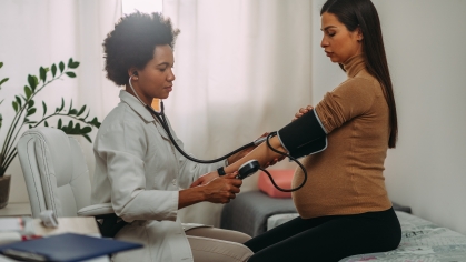 image of medical provider taking blood pressure of a pregnant female presenting person