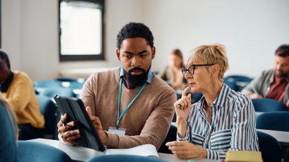 Teacher providing instruction to older adult via ipad