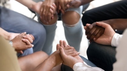 group of people sitting next to each other in a circle holding hands