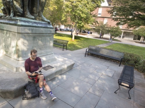 Student reading beneath statue