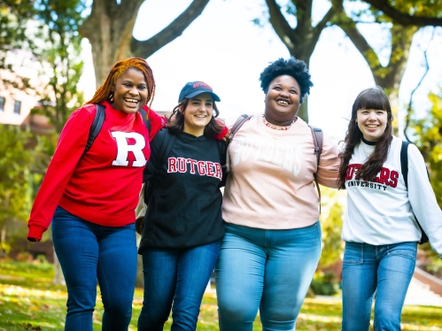 group of female presenting students in rutgers sweatshirts smiling at the camera outside