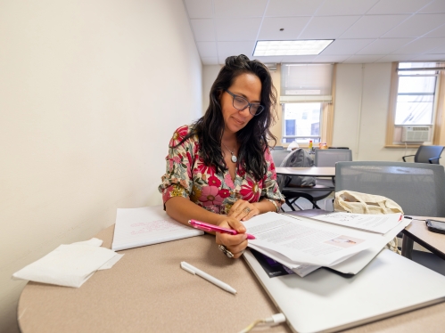 Depth photo of a female presenting adult sitting at a round table reviewing papers in a well lit room