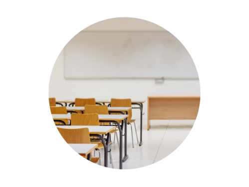 Classroom with empty chairs facing a teacher's desk and whiteboard