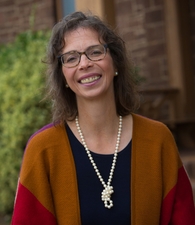 White woman with a cardigan sweater and necklace smiling